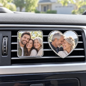 May include: Two car air vent clips featuring custom photo displays. One clip is square-shaped and shows a man and woman smiling together. The other clip is heart-shaped and displays a photo of an older couple smiling at each other.