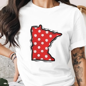 May include: White t-shirt featuring a red polka-dotted outline of the state of Minnesota with a black border. The shirt is made of a soft material and is suitable for casual wear.
