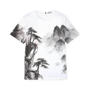 May include: A white short-sleeve t-shirt featuring a black and gray ink wash style landscape print. The design depicts jagged mountain peaks, pine trees, and rocky cliffs across the front. A size L label is visible at the inner neckline.
