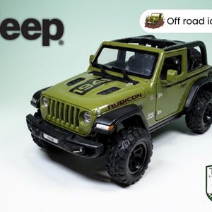 Könnte beinhalten: Olivgrünes Jeep Rubicon Modell mit schwarzen Akzenten und großen Offroad-Reifen. Auf der Motorhaube steht die Zahl "1941" und das Wort "RUBICON". Das Bild enthält das Wort "Jeep" und eine "Off road icon!" Grafik.