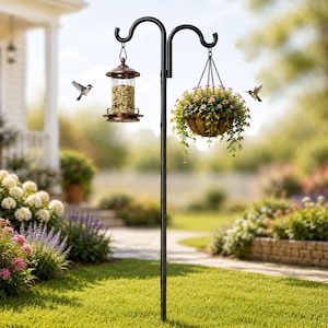 May include: A black metal bird feeder pole with two curved arms. One arm holds a copper-colored bird feeder filled with seeds, and the other holds a hanging basket of pink flowers. A hummingbird and a small bird are flying nearby.