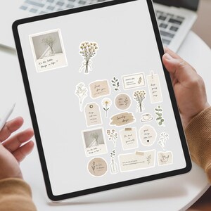 以下が含まれることがあります： ベージュとクリーム色のステッカーコレクションが表示されたデジタルタブレット画面。植物のイラスト、"It's the little things in life"や"Lovely days"といった手書き風のテキスト、小さなコーヒーカップのアイコンがデザインされています。