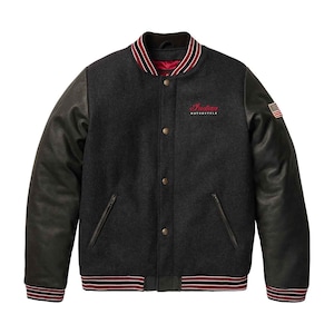 Puede incluir: Chaqueta universitaria gris carbón con mangas de cuero negro. La chaqueta presenta el texto "Indian MOTORCYCLE" en rojo en el pecho, un pequeño parche de la bandera estadounidense y ribetes a rayas rojas y blancas en el cuello, los puños y el dobladillo.