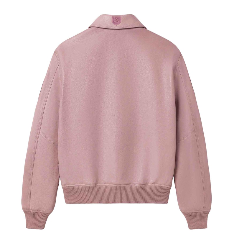 May include: A dusty rose bomber jacket with a collared neckline and ribbed cuffs and hem. The back of the jacket features a small emblem on the collar. The jacket has long sleeves and a relaxed fit, suitable for casual wear.