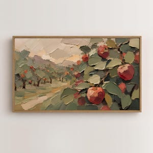 May include: A rectangular oil painting in a wooden frame depicting an apple orchard with thick, textured brushstrokes. The scene features red apples hanging from green-leafed branches in the foreground, with a path leading into the distance.
