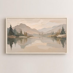 May include: A rectangular landscape painting in a light-colored frame featuring a mountain range and trees reflected in a calm body of water. The artwork uses a palette of muted beige, cream, gray, and soft green tones with visible thick paint texture.