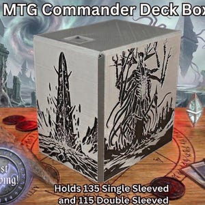Op de afbeelding: Een grijze MTG Commander Deck Box met zwarte afbeeldingen op de zijkanten. De doos biedt ruimte aan 135 kaarten met enkele sleeves of 115 kaarten met dubbele sleeves. Op een houten oppervlak.