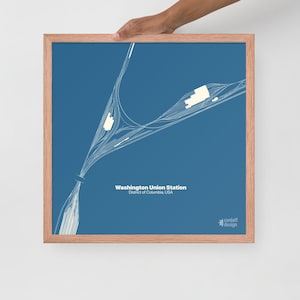 May include: A framed print featuring a detailed white line drawing of Washington Union Station on a blue background. The text "Washington Union Station, District of Columbia, USA" is displayed. The frame is a light brown color.