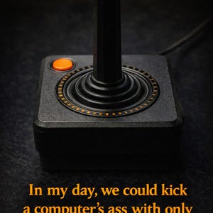 Puede incluir: Un joystick Atari negro con un botón naranja y un mango negro. El joystick tiene un diseño circular alrededor de la base. El texto en naranja dice: "In my day, we could kick a computer's ass with only one button."