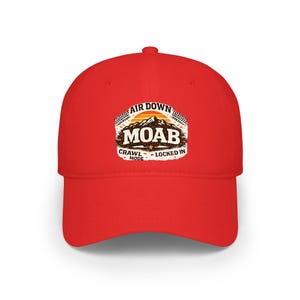 Puede incluir: Gorra de béisbol roja con un diseño de Moab. El diseño incluye el texto "AIR DOWN MOAB CRAWL MODE - LOCKED IN" con un gráfico de montaña y puesta de sol. La gorra está hecha de un material duradero.