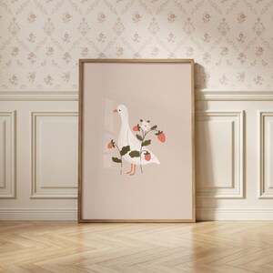 May include: A framed vertical wall art print featuring a white goose with an orange beak and feet, surrounded by green strawberry plant stems with red strawberries and a single white flower, set against a solid light beige background.