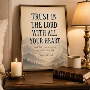May include: A framed wall art print featuring a mountain landscape and the text: TRUST IN THE LORD WITH ALL YOUR HEART and lean not on your own understanding. Proverbs 3:5. The print uses dark blue lettering against a cream background with a mountain scene.