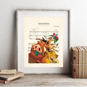 May include: Framed print featuring the words "HAKUNA MATATA" above sheet music. The image includes cartoon characters from The Lion King: Simba, Timon, Pumbaa. The print is in a white frame and rests on a wooden shelf with books.