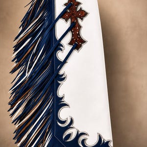 Puede incluir: Chaps de cuero blanco con ribete azul oscuro y recortes decorativos, largos flecos azules y blancos, y una aplicaci&oacute;n de cuero marr&oacute;n con dise&ntilde;o floral en forma de cruz. Un cintur&oacute;n de cuero negro con hebilla est&aacute; sujeto a la cintura.