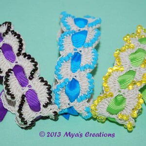 May include: Three crocheted bracelets with different colored ribbon and beads. The bracelets are white with purple, blue, and green ribbon.