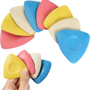 May include: A collection of triangular tailor's chalk pieces in various colors including blue, pink, yellow, and off-white. The chalks are arranged in a fan shape at the top, with a smaller cluster held in the foreground, showing a smooth texture.