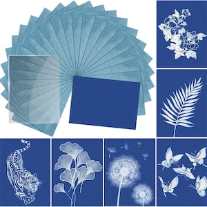 May include: A collection of blue and white art prints. The prints feature various designs, including flowers, butterflies, a tiger, and dandelions. The prints are arranged in a fan shape, with a solid blue rectangle in the center.