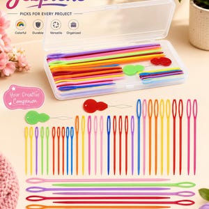 Op de afbeelding: Een set kleurrijke plastic wolnaalden en draadinrijgers in een doorzichtige rechthoekige opbergdoos. De collectie bevat verschillende lengtes en tinten roze, geel, groen, blauw, oranje en paarse naalden, samen met rode en groene draadinrijgers.