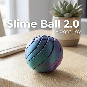 Peut inclure: Un jouet anti-stress sphérique avec une finition métallique irisée dans des tons de sarcelle, de violet et de bleu. Le jouet est segmenté, avec des lignes courbes créant un effet de spirale. Le texte sur l'image indique "Slime Ball 2.0 Fidget Toy."