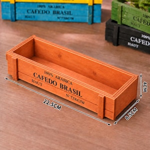 May include: A rectangular orange wooden crate with black text reading 100% ARABICA CAFEDO BRASIL HAUT N°73843W. The crate measures 22.5 cm in length, 8.5 cm in width, and 4 cm in height, as indicated by the visible measurement markings.