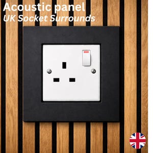 May include: Acoustic panel with a black UK socket surround. The white electrical outlet has a switch in the on position. The panel is made of vertical wooden slats in shades of brown and black. The text "Acoustic panel UK Socket Surrounds" is at the top.
