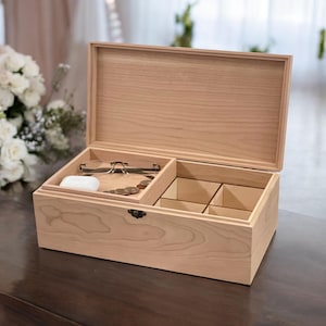 May include: A light wood box with a hinged lid, divided into compartments. The box contains a pair of glasses, a small white case, and several coins.
