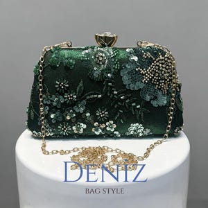 Op de afbeelding: Een donkergroene rechthoekige clutch met ingewikkeld bloemenborduurwerk van bijpassende groene lovertjes en kralen. De tas heeft een goudkleurig metalen frame, een kristalachtige sluiting en een afneembare gouden ketting. Tekst: DENIZ BAG STYLE.