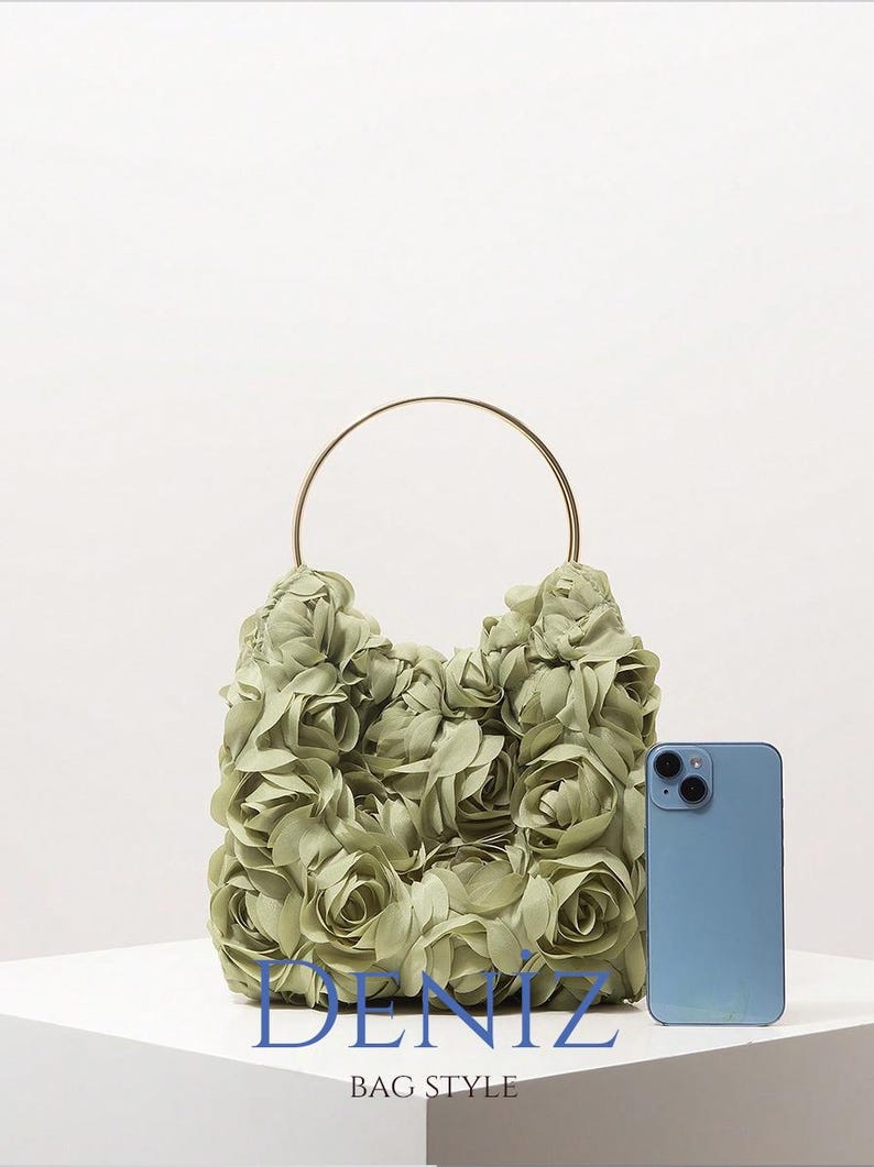 May include: A sage green handbag with a floral design, featuring a gold-coloured handle. The bag is next to a blue smartphone. The text "DENIZ BAG STYLE" is at the bottom.