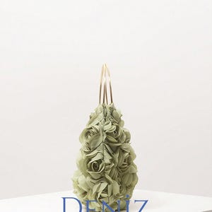 May include: A light green handbag with a floral design. The bag is covered in fabric roses and has gold-coloured handles. The text "DENIZ BAG STYLE" is printed on the front of the bag.