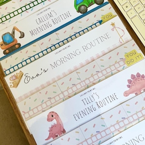 May include: A collection of personalized routine charts featuring colorful illustrations of construction vehicles, dinosaurs, and crowns. Each chart includes text such as Callum's Morning Routine, Eva's Morning Routine, and Tilly's Evening Routine.
