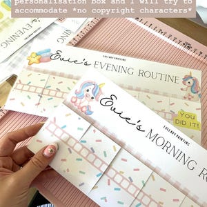 May include: A set of printed routine charts featuring a unicorn graphic, pastel confetti patterns, and the text Evie's Morning Routine and Evie's Evening Routine. The charts include interactive flaps and a You Did It label by Lullaby Printing.