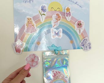 Könnte beinhalten: Eine Belohnungstafel mit der Aufschrift Pippa's Reward Rainbow, die einen bunten Regenbogen, eine lächelnde Sonne und verschiedene Aufkleber wie eine Prinzessin, eine Fee, einen Schmetterling und ein Einhorn zeigt. Ein holografischer Beutel hängt darunter.