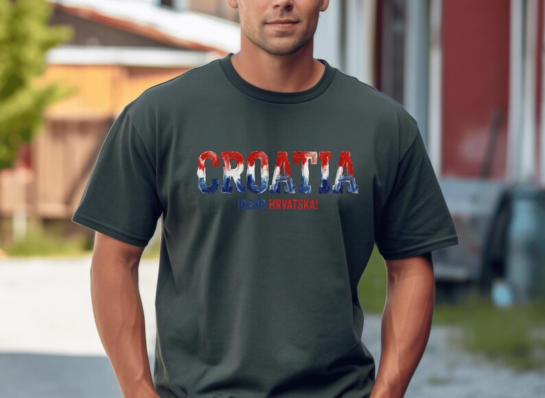 Pu&ograve; includere: Una t-shirt a maniche corte grigio scuro con la parola CROATIA in grandi lettere in grassetto riempite con un motivo rosso, bianco e blu. Sotto il testo principale, la parola HRVATSKA &egrave; stampata in lettere rosse pi&ugrave; piccole sul davanti.