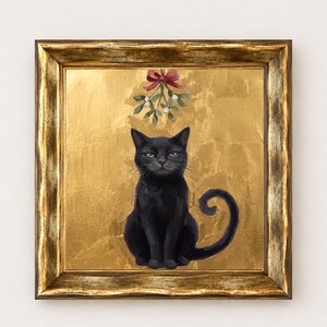 May include: A framed painting of a black cat sitting centered against a textured gold background. Above the cat, a sprig of mistletoe with white berries is tied with a red ribbon. The artwork is enclosed in a distressed gold-toned frame.
