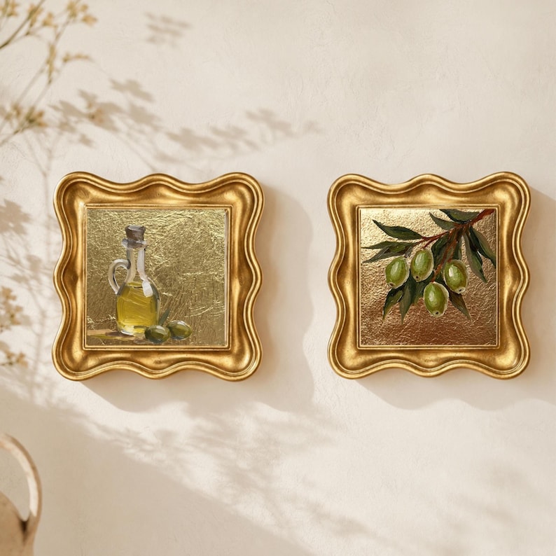 May include: Two framed oil paintings with gold ornate frames. One depicts an olive oil bottle with olives, the other a branch with green olives. Both paintings have a gold background.