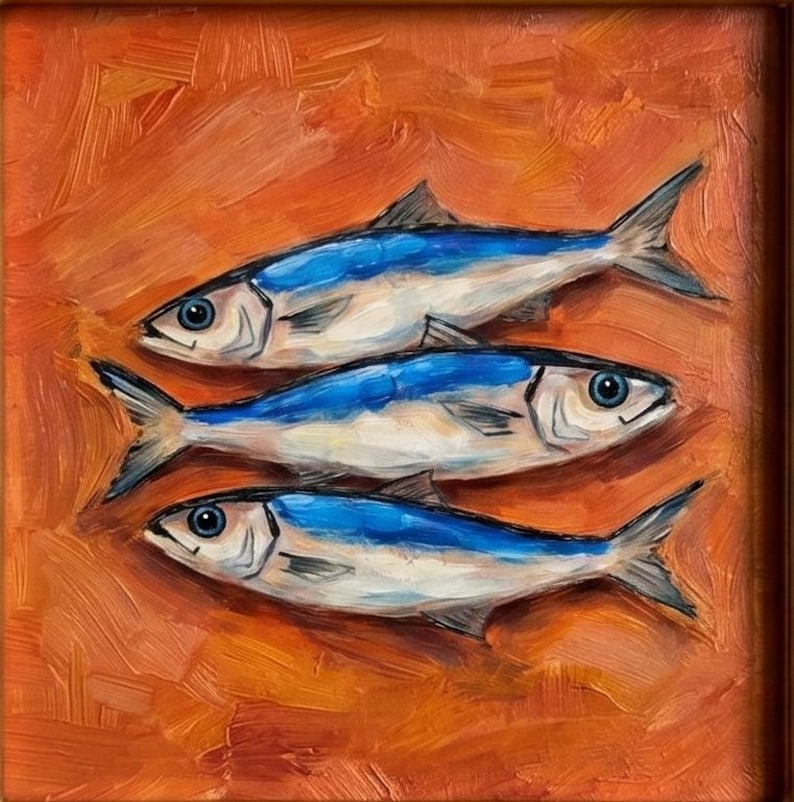 May include: Oil painting of three fish with blue and white bodies, set against an orange background. The fish are arranged horizontally, with visible details in their fins and eyes. The artwork is framed in a brown wooden frame.