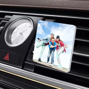 May include: A white square car air vent clip with a photo of three friends smiling and posing for a picture. The photo is printed on a glossy surface.