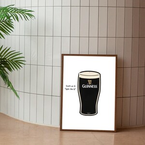 May include: A framed print featuring a stylized Guinness pint glass. The glass is black with a white head, and the Guinness logo is visible. Text on the left reads "Scott an G 'Split the G'". The frame is brown.