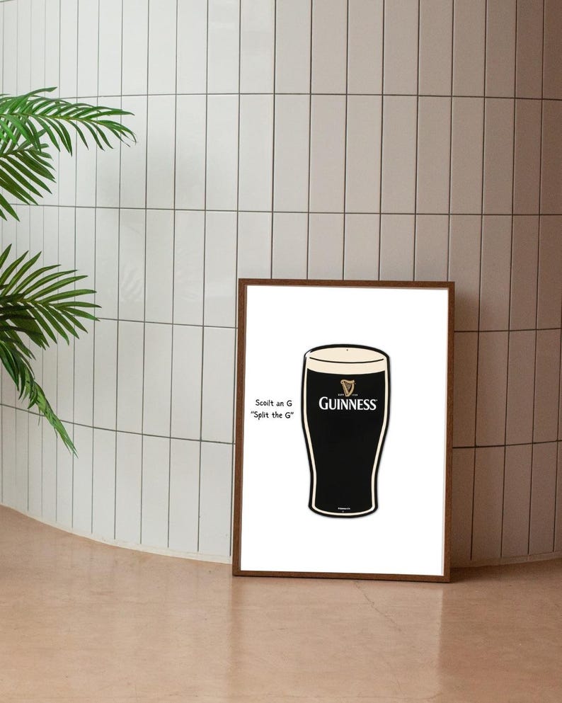 May include: A framed print featuring a stylized Guinness pint glass. The glass is black with a white head, and the Guinness logo is visible. Text on the left reads "Scott an G 'Split the G'". The frame is brown.
