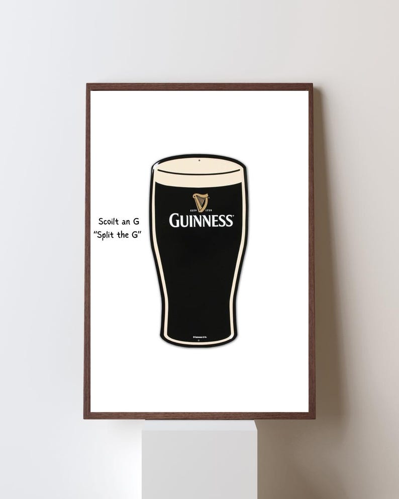 May include: A framed print featuring a stylized illustration of a pint of Guinness stout. The glass is black with a creamy white head, and the Guinness logo is prominently displayed. Text on the left reads "Scoil an G, Split the G."