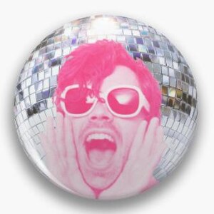 May include: A circular pin-back button featuring a monochromatic hot pink graphic of a person with their hands on their cheeks and mouth open in an expression of surprise, wearing white-rimmed sunglasses against a reflective silver disco ball.