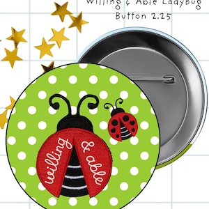 May include: A round pin-back button featuring a lime green background with white polka dots. The design includes two red ladybugs with black spots and antennae. The larger ladybug has the white text "willing & able" printed on its wings.