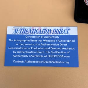 May include: A blue and white Authentication Direct certificate. The certificate states that the autographed item was witnessed and deemed authentic by Authentication Direct. Contact information is provided.