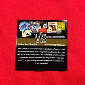 May include: A black and gold Certificate of Authenticity card with the text "VS" and "Certificate of Authenticity". The card includes images of sports memorabilia and the text "Online Verification" and "www.vsautographs.com".