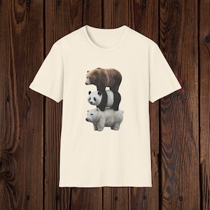 May include: Cream-colored t-shirt featuring a stacked image of three bears: a brown bear on top, a panda in the middle, and a white bear at the bottom. The bears are realistically rendered.