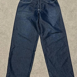 Puede incluir: Vaqueros de mezclilla azul oscuro con dise&ntilde;o de pernera ancha. Los vaqueros tienen un estilo cl&aacute;sico de cinco bolsillos, cierre de bot&oacute;n y cremallera, y el nombre de la marca "FIS6R" es visible en la cintura. Los vaqueros est&aacute;n planos sobre una superficie neutra.