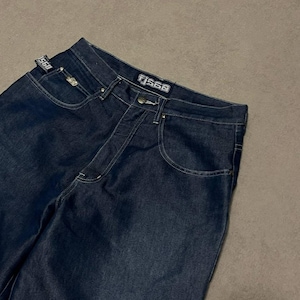 Puede incluir: Vaqueros de mezclilla azul oscuro con costuras blancas. Los vaqueros tienen un dise&ntilde;o cl&aacute;sico de cinco bolsillos y un corte de pierna recta. El nombre de la marca "TJ560" es visible en la cintura y una peque&ntilde;a etiqueta en el bolsillo delantero.