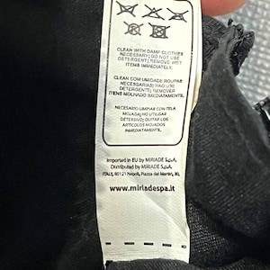 May include: A white clothing tag with care instructions and the text "CLEAN WITH DAMP CLOTHES NECESSARY; DO NOT USE DETERGENT; REMOVE WET ITEMS IMMEDIATELY." The tag also includes the website address www.miriadespa.it.