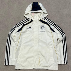 Könnte beinhalten: Weiße Adidas Chelsea FC Kapuzenjacke mit marineblauen und schwarzen Akzenten. Mit Adidas-Logo, Chelsea FC-Wappen und Samsung-Logo. Enthält schwarze Streifen auf den Ärmeln und den Text "CHELSEA FC".