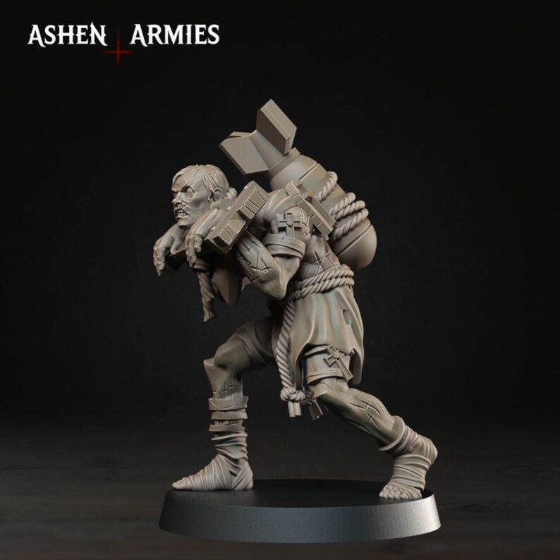 May include: A grey miniature figurine of a hunched figure carrying a large bomb on their back, secured with thick rope. The figure wears tattered clothing and wraps around their legs. The text ASHEN ARMIES is visible in the top left corner.